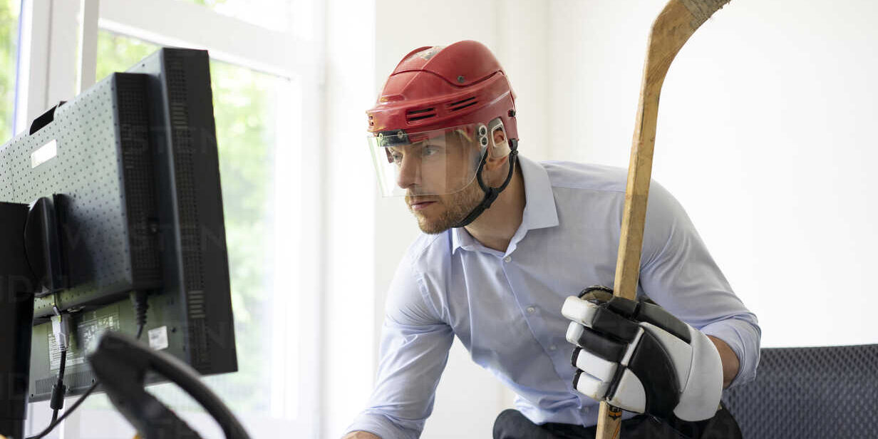 Businessman dressed up as ice hockey player working at desk in office